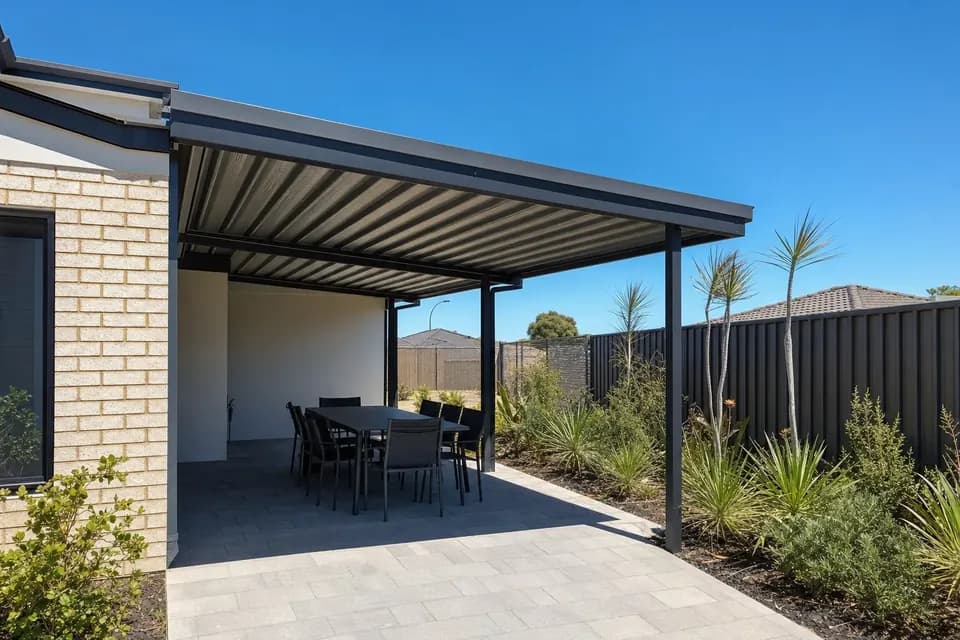 Skillion patio with a charcoal Colorbond roof shading an outdoor dining table on a hot, clear Perth day
